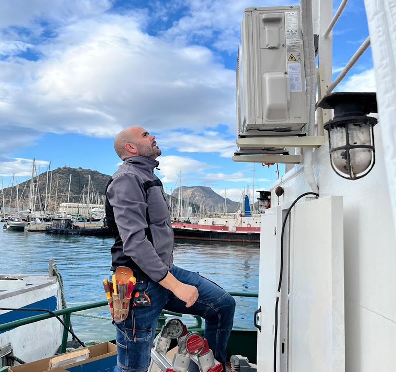 Instalación de aire acondicionado en barco pesquero en Cartagena, Murcia Técnico instalando aire acondicionado en embarcación atracada en el puerto de Cartagena